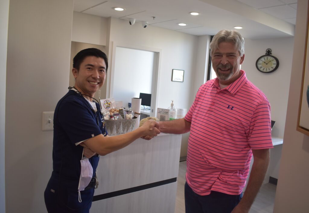 Employing acceptable etiquette in the form of a hand clasp, Duayne Driscoll presents Dr. Han with BVA Challenge Coin.