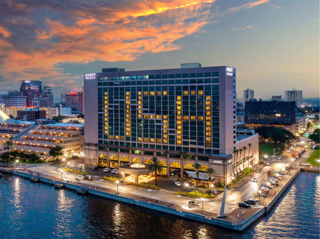 View of the Hyatt Regency Jacksonville Riverfront Hotel at dusk with windows lit up that spell out USA.