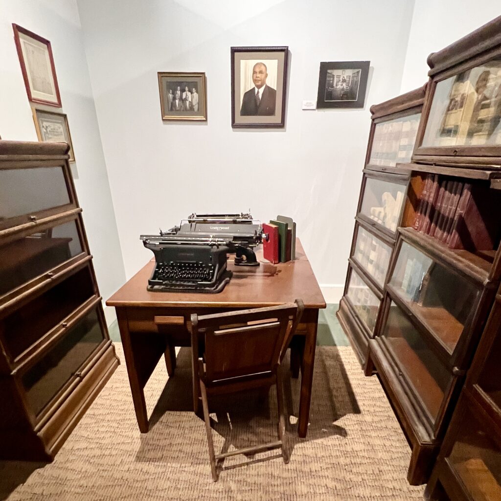 An exhibit in the theater museum; there are bookcases on either side with a desk and a chair in the middle. There is a typewriter on the desk.