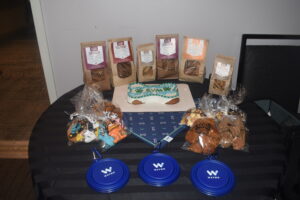 Gifts for BVA 2023 National Convention Bow Wow Lounge users; pictured are packs of dog biscuits, dog treats, handkercheifs, and frisbees.